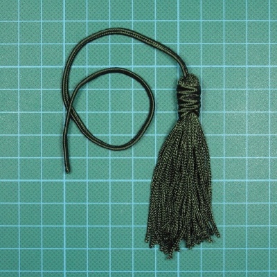 Borla preta com cordão sobre tapete de corte verde com linhas de grade