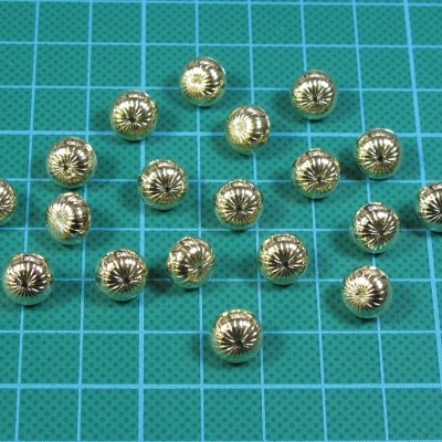 Botões dourados metalizados com padrão radial em superfície de corte azul com grade.