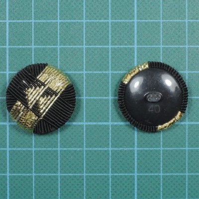 Dois botões pretos com detalhes dourados em fundo quadriculado azul