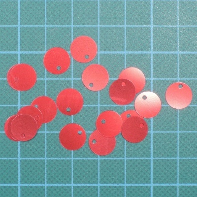 Lantejoulas vermelhas circulares sobre superfície verde quadriculada