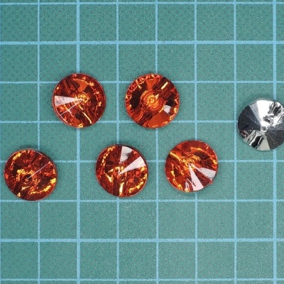 Seis botões redondos, cinco laranja translúcidos e um prateado, sobre base quadriculada verde