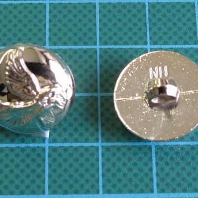 Dois botões metálicos prateados sobre tapete de corte verde