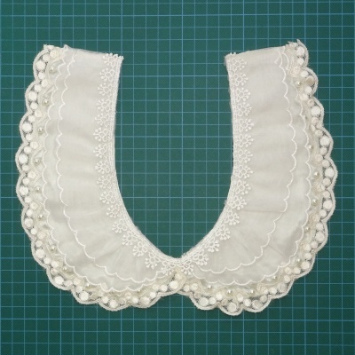Gola branca bordada com renda em fundo verde quadriculado