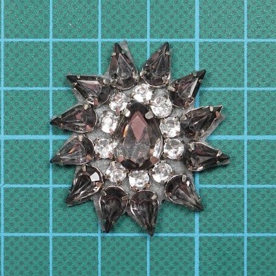 Aplicação Redonda 4,2cm x 3,5cm com Pedras cosidas sobre base de feltro com cola.