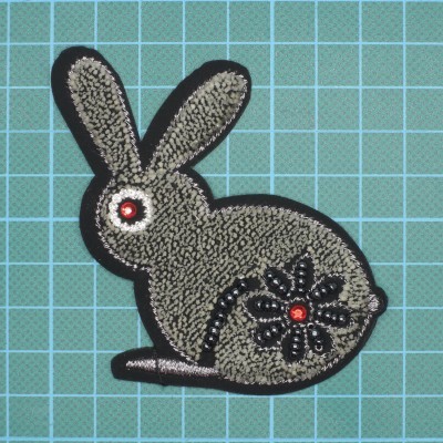 Patch bordado em forma de coelho cinza com detalhes em preto, prateado e vermelho