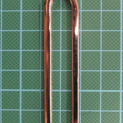 Clipe de papel metálico dourado numa superfície quadriculada verde