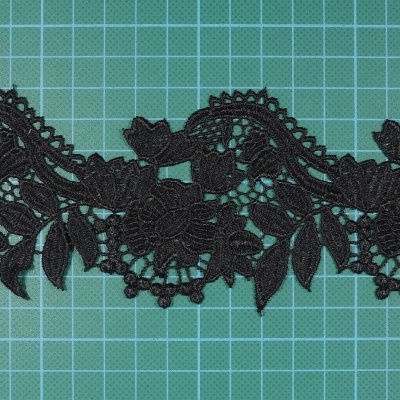 Renda preta com padrão floral sobre fundo verde quadriculado