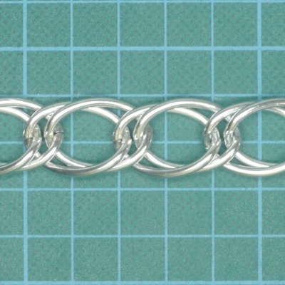 Corrente prateada com elos ovais sobre superfície verde com grade branca