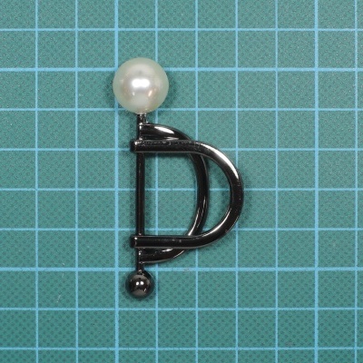 Brinco em forma de letra D prateado com pérola branca sobre fundo quadriculado azul claro