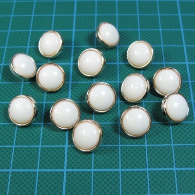 Botões brancos com borda dourada sobre superfície verde quadriculada