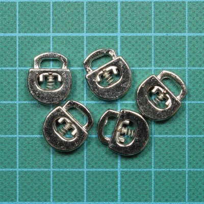 Cinco peças metálicas pequenas sobre superfície verde quadriculada