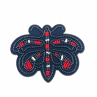 Patch em forma de insecto com contas bordadas em vermelho, branco e cinza num tecido azul escuro