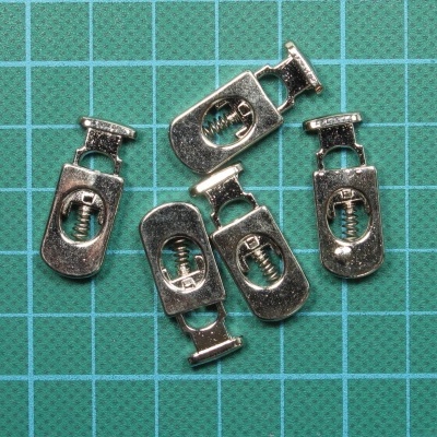 Cinco fechos metálicos prateados sobre superfície verde de grelha