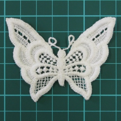 Aplicação bordada branca em forma de borboleta sobre fundo quadriculado verde