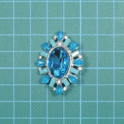 Broche com pedras azuis e detalhes prateados sobre fundo de grade azul