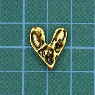 Pendente dourado em forma de coração sobre fundo quadriculado verde