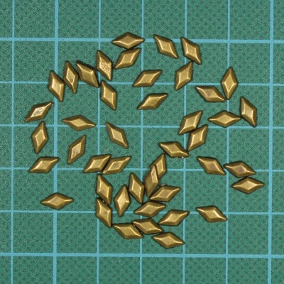 Peças losango douradas sobre base de corte verde com grelha