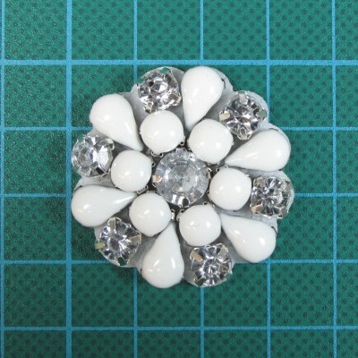 Aplicação 4,4cm com Pedras Cristal e Brancas cosidas sobre base de feltro com cola.