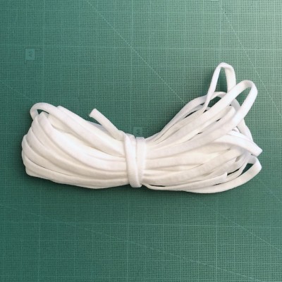 Fio elástico branco enrolado sobre superfície verde quadriculada