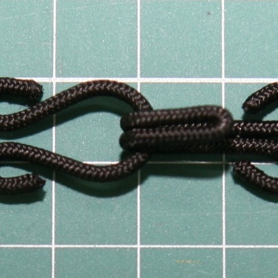 Gancho de roupa preto em tecido sobre superfície quadriculada verde-água