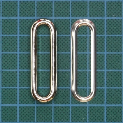 Dois elos metálicos alongados, um dourado e um prateado, sobre base azul quadriculada