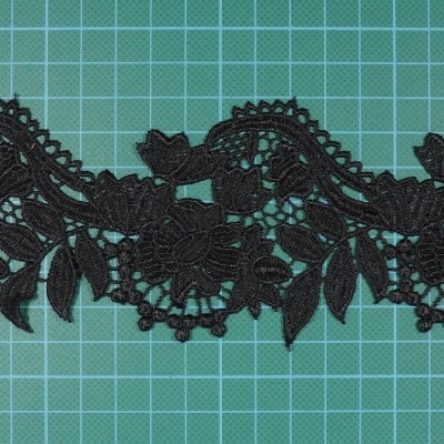 Renda preta com padrão floral sobre base quadriculada verde