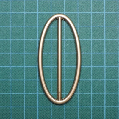 Fivela de metal dourado oval sobre fundo verde quadriculado