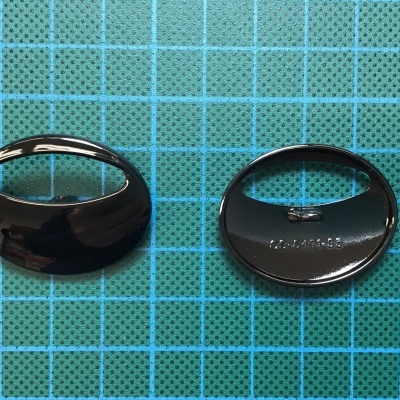 Par de botões negros de metal com inscrição sobre fundo quadriculado azul