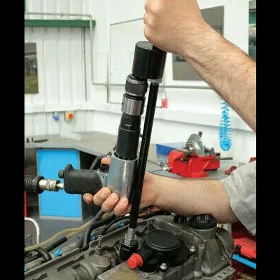 Mão usando ferramenta pneumática num motor em oficina