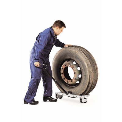Homem com fato de trabalho a levantar pneu grande e sujo usando ferramenta e carrinho de transporte.
