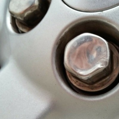 Porca hexagonal de metal prateada numa superfície metálica prateada