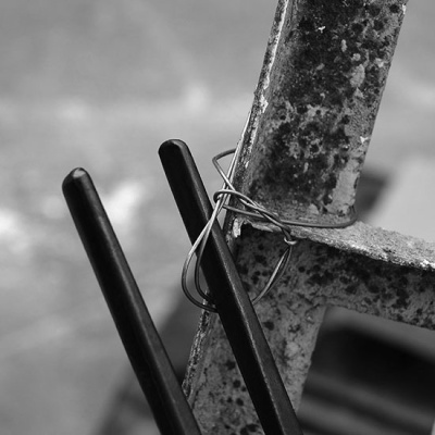 Objeto metálico enferrujado e objetos pretos cilíndricos segurados por arame fino