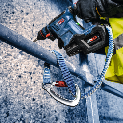 Operador com colete e luvas a usar furadeira azul Bosch num corrimão com mosquetão e fita azul
