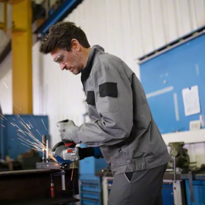 Homem a usar esmerilhadora elétrica em oficina industrial