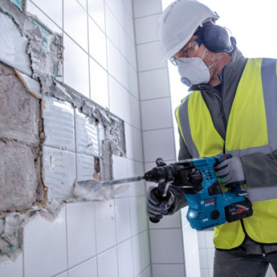 Homem com equipamento de proteção a demolir parede de azulejos