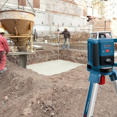 Equipamento de nivelamento a laser BOSCH num canteiro de obras com trabalhadores e fundação em construção