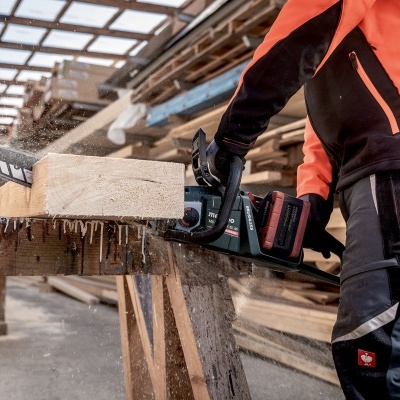 Pessoa a usar motosserra para cortar madeira num local de trabalho