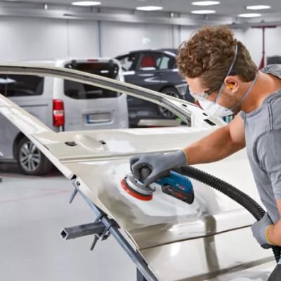 Homem a polir porta de carro branca numa oficina automóvel