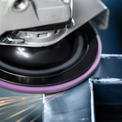 Lixadora elétrica a trabalhar numa superfície metálica com faíscas