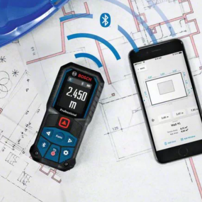 Instrumento de medição digital Bosch sobre plantas arquitetónicas com telemóvel e capacete azul