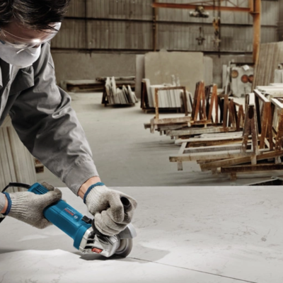 Pessoa a cortar placa branca com esmerilhadora num armazém