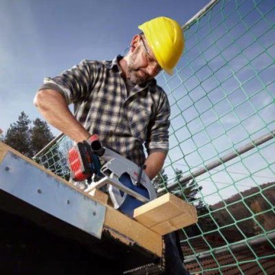 Homem a cortar madeira com serra elétrica numa obra ao ar livre