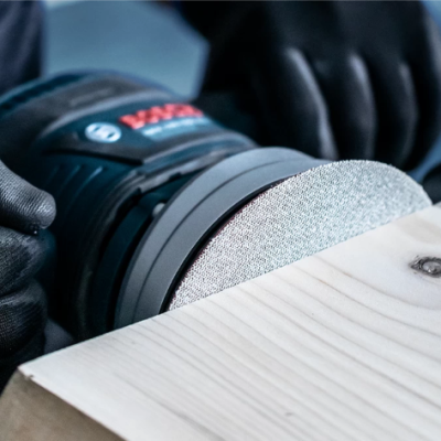 Lixadora elétrica VMAX a lixar madeira clara com luvas pretas