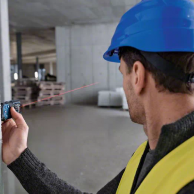 Homem a medir distância com medidor a laser numa parede branca