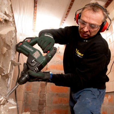 Pessoa a usar ferramenta elétrica Metabo para perfurar parede interior em construção