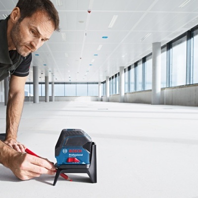 Homem utilizando nível laser Bosch em chão claro num espaço amplo e moderno