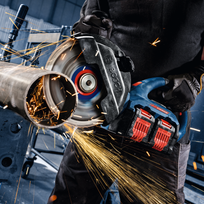 Pessoa usando rebarbadora elétrica BOSCH a cortar tubo metálico gerando faíscas