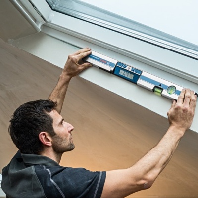 Homem mede caixilho de janela com nível de bolha