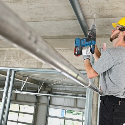 Homem a furar o teto de cimento numa construção interior