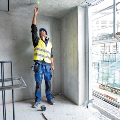 Trabalhador de construção a medir com dispositivo luminoso no teto